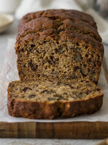 Sliced banana date loaf on a wooden plate.