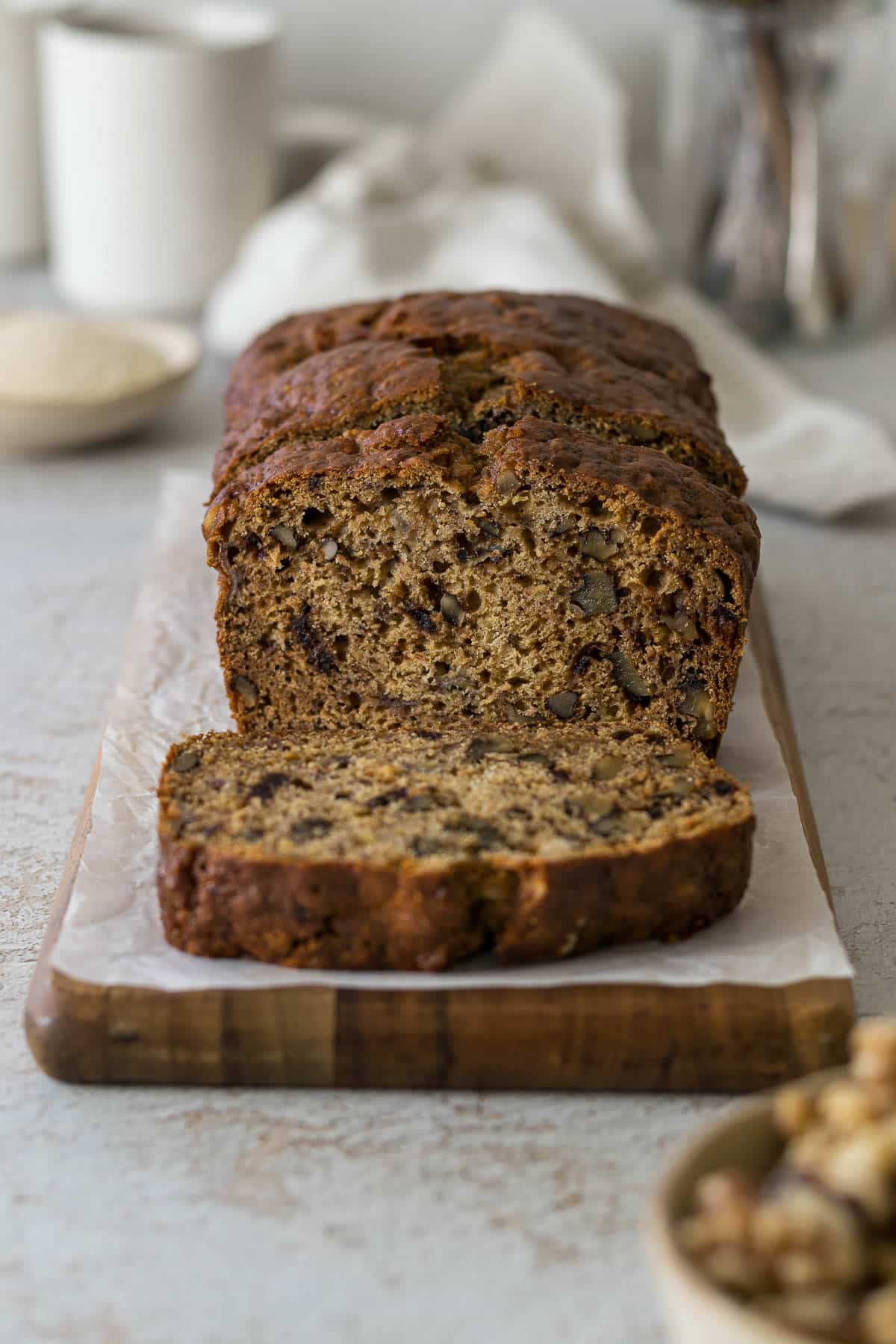 Sliced banana date loaf on a wooden plate.