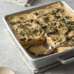 Peppermint crisp tart in a serving dish, with a serving spoon, sprinkled with pieces of peppermint crisp.